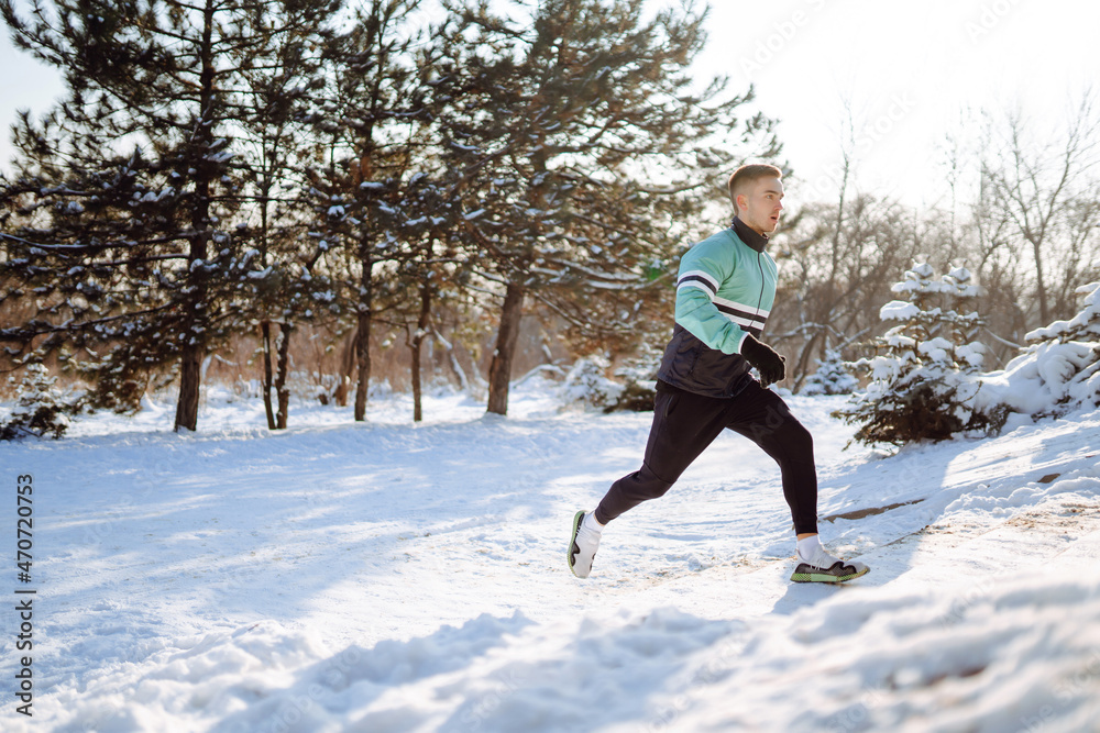 Young sportsman doing exercises in forest at sunny, snowy winter day. Outdoor fitness, cardio exercises, winter fitness, Active life. Young sportsman doing exercises in forest at sunny, snowy winter day. Outdoor fitness, cardio exercises, winter fitness, Active life.
