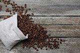 Bag with roasted coffee beans on wooden table, flat lay. Space for text