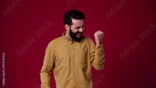 the guy got his dream job, he shines with joy, he achieved his goal, a positive mood, a goal, a mission completed, he is dark-haired, bearded, wears a brown shirt, the background is red