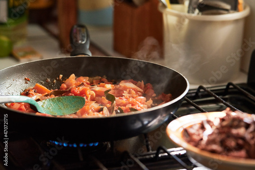 Carne en sartén con cebolla y tomate. Comida tradicional hecha en casa en un estufa por la tarde.