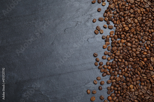 Many roasted coffee beans on black table  flat lay. Space for text
