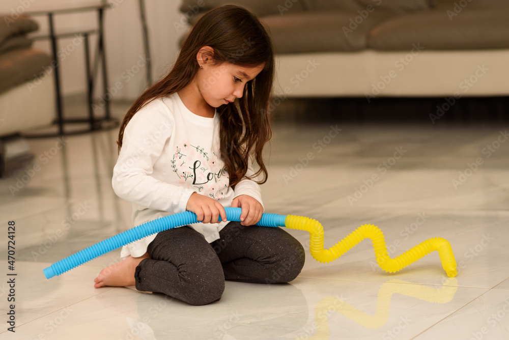 Young Little Girl Sitting On The Floor At Home Playing Pop Tube Toy-New  Fidget Toy, Popular With Kids, Helps Them To Concentrate. Child Playing  With The Tubes Fidget Toy At Kindergarten. Stock-Foto