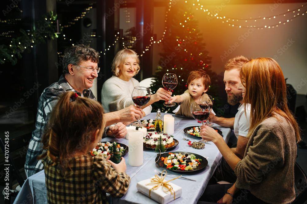 Vibrant big family on christmas gathering. Clinking wine glasses, celebrating