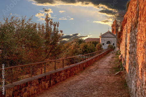 Montalcino, Tuscany, Italy. August 2020. Amazing image at the golden hour. A church just outside the walls of the historic village is enveloped in the warm light of the sunset.