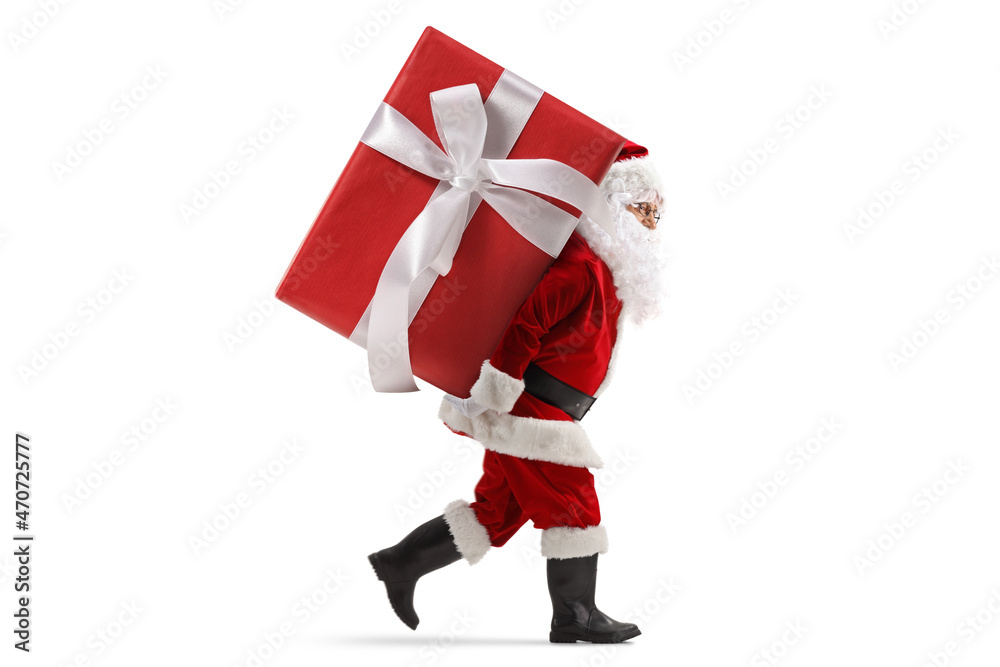Full length profile shot of santa claus carrying a big preset on his back Full length profile shot of santa claus carrying a big preset on his back