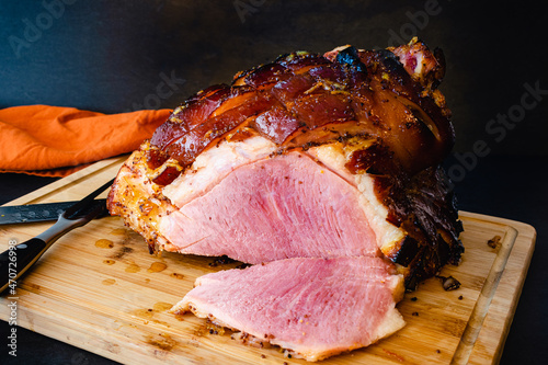 Bourbon Orange Glazed Ham on a Bamboo Carving Board: Sliced bone-in glazed ham on a wooden cutting board