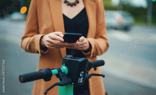 Woman using app on smartphone to unlock electric scooter on the street.