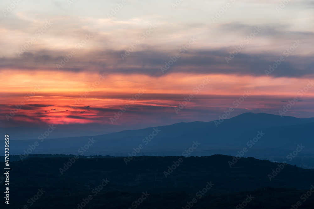 Sunset with layers of hills and mountains, soft focus. Mountain layers in sunset. Blue mountains and last sun lights landscape.