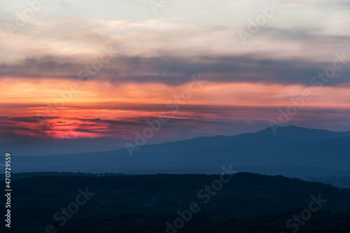 Sunset with layers of hills and mountains, soft focus. Mountain layers in sunset. Blue mountains and last sun lights landscape.