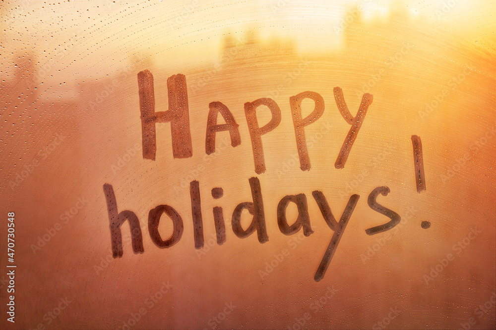Words happy holidays on muddy wet orange window in city on sunset Words happy holidays on muddy wet orange window in city on sunset