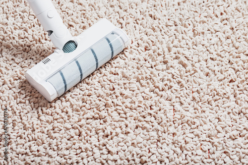A white turbo brush of a cordless vacuum cleaner on the carpet. Indoor cleaning concept
