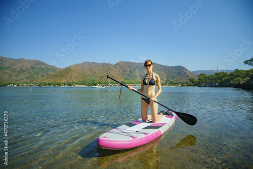 Woman paddling on paddleboard in sea. SUP board activity on sea
