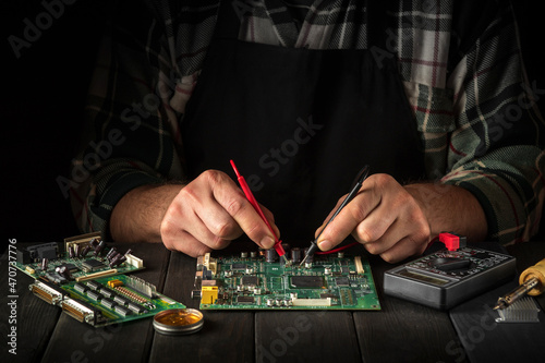 Computer or electronics repair. Master tester checks the electronic board in the service workshop.