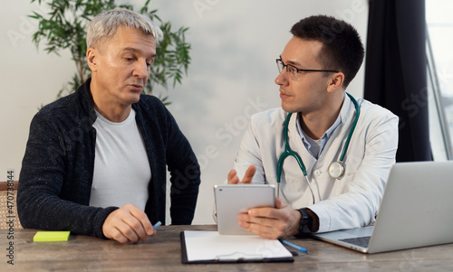 Consultation visit to a medical office. Male client at the clinic. The doctor communicates with patients in his office.