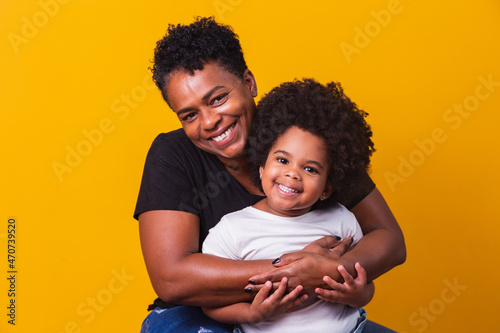 happy mother's day! Adorable sweet afro-american mother with cute little daugh. Older mother with her daughter on yellow background. photo