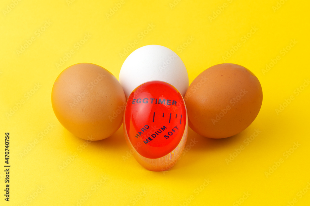 Modern red plastic kitchen timer and three eggs on a yellow background. Boiled eggs. Modern red plastic kitchen timer and three eggs on a yellow background. Boiled eggs.