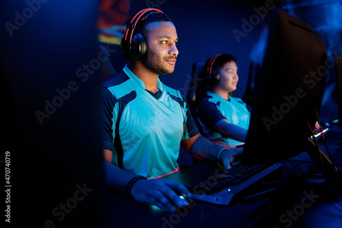 Obraz na plátně Young esports player concentrated on game wearing wired headset while playing on