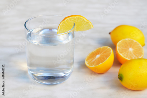  A glass of lemon juice and lemons around on a table.