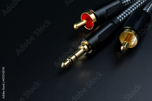 The gold-plated RCA connectors and TRS connector for sound transmission, audio cable for excellent sound quality. White-red audio connectorson black background. Copy space photo