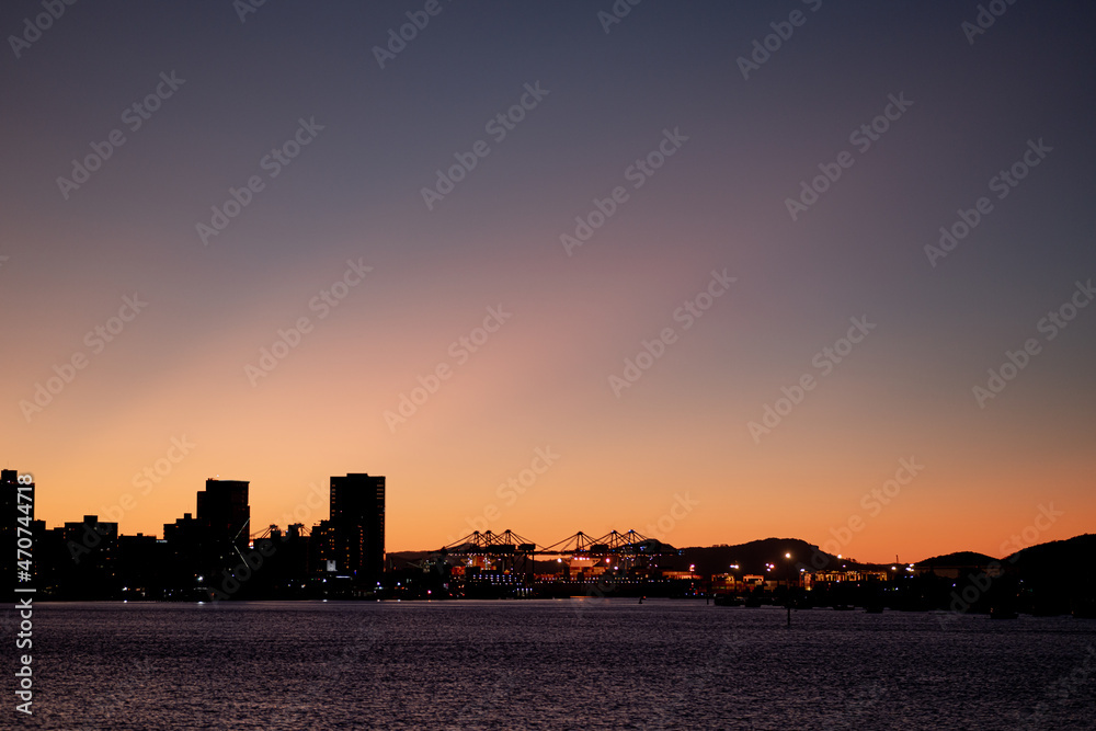 Sunset in the city with buildings and ships harbor, sea, river and sky. City at night.