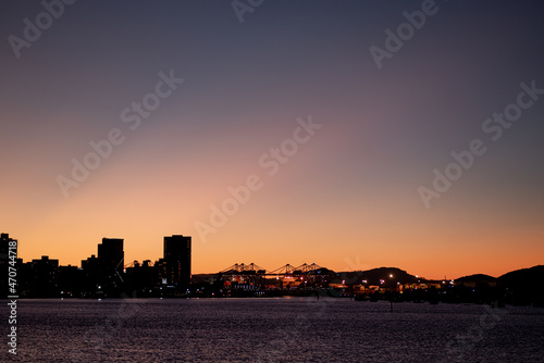 Sunset in the city with buildings and ships harbor, sea, river and sky. City at night.