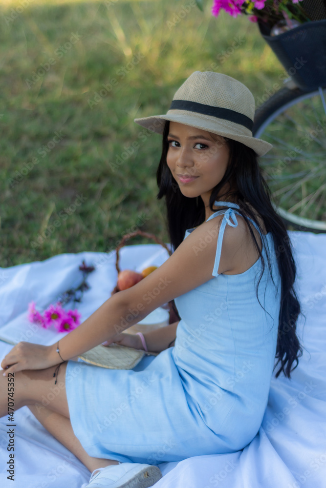 Fototapeta premium portrait of young brunette woman looking at camera sitting on a white blanket on a picnic.