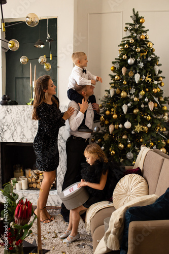 Happy parents and their chilfren daughter and son waiting for Christmas at home and decorating Christmas tree. Family Christmas at home. photo