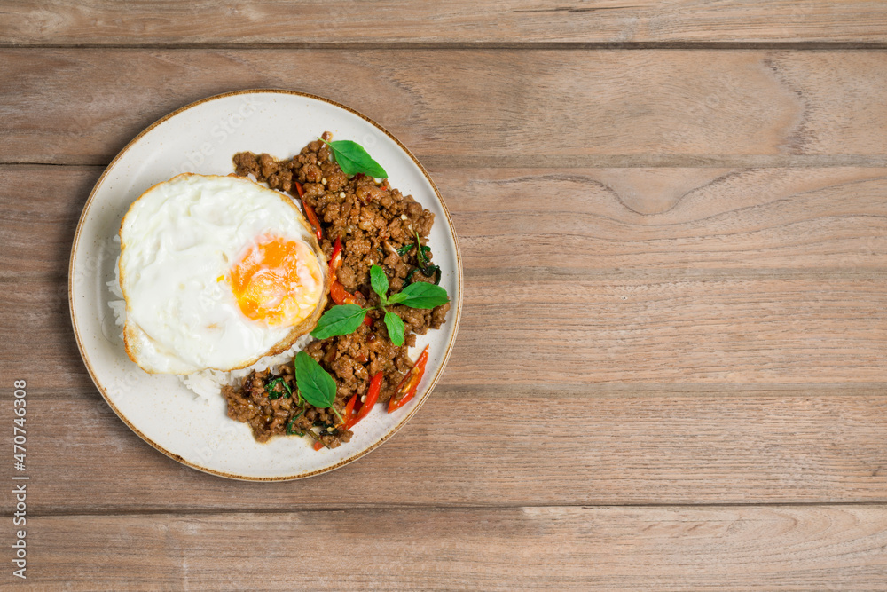 Minced pork with basil rice with fried egg, laying on the wooden floor, top view Minced pork with basil rice with fried egg, laying on the wooden floor, top view