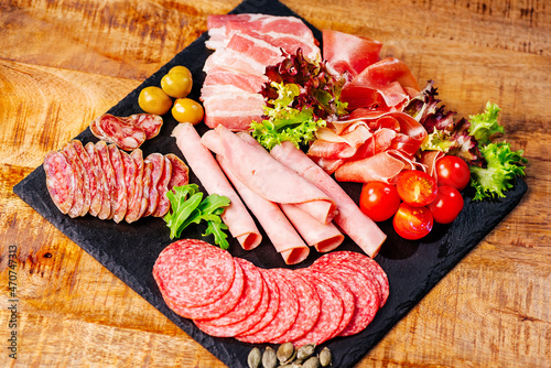 Assorted meats and sausages, olives and spices, close-up.Slices of delicious spanish sausage salami. Healthy food concept.Top view.Various types of meat and sausages on wooden table.
