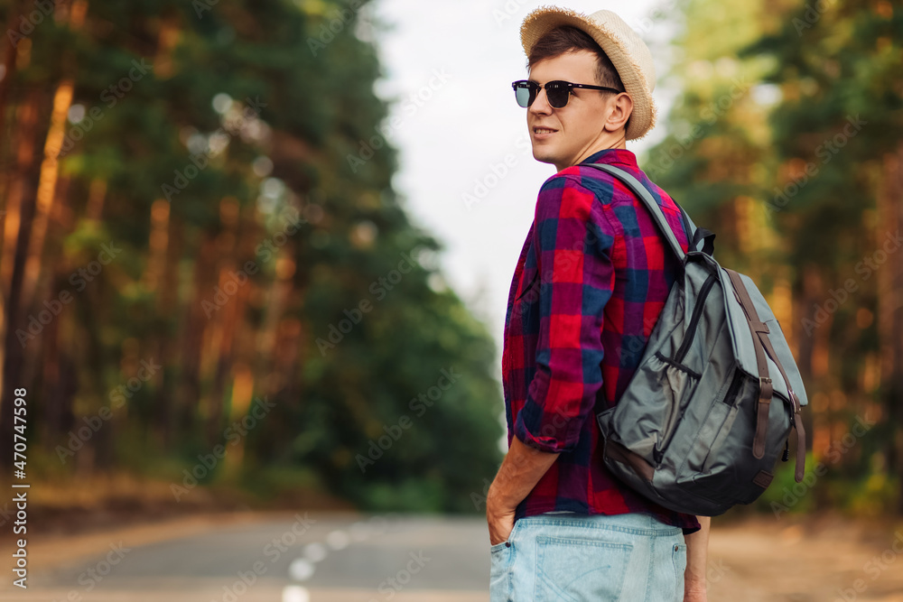tourist man in a hat walking on a trail in the forest. Strong sporty man traveling with backpack on forest background tourist man in a hat walking on a trail in the forest. Strong sporty man traveling with backpack on forest background