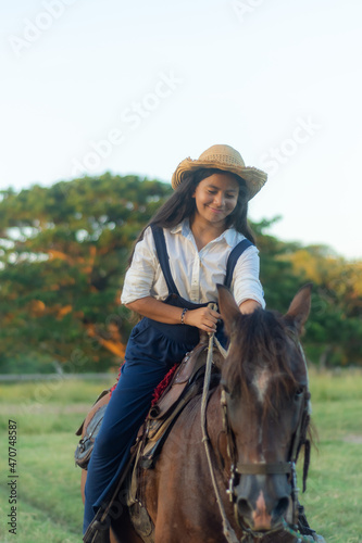 young brunette girl long black hair smiling riding a horse in the field on a sunny day 