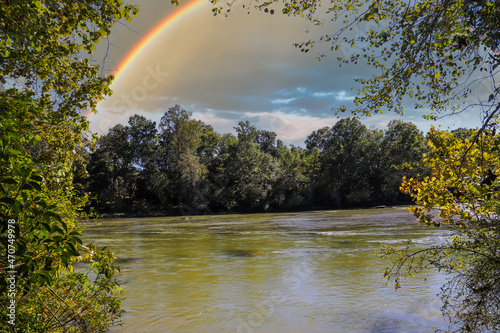 a shot of the silky green waters of the Chattahoochee river surrounded by lush green and autumn colored trees with a rainbow at Jones Bridge Park Trail in Johns Creek Georgia USA photo