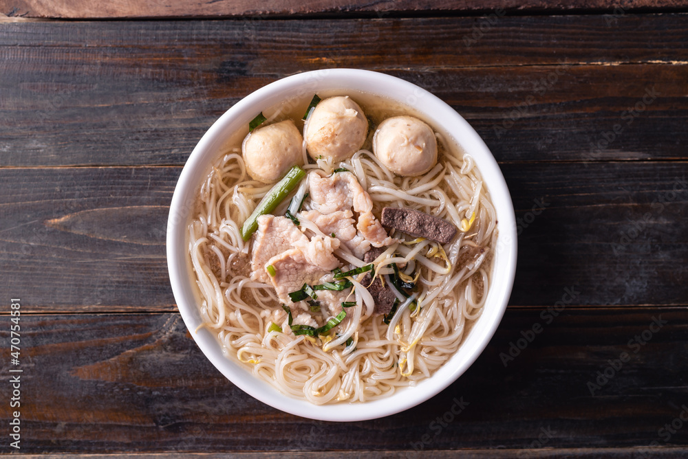 Rice noodles soup with pork and pork ball in a bowl on wooden background, Thai noodles soup, Table top view Rice noodles soup with pork and pork ball in a bowl on wooden background, Thai noodles soup, Table top view