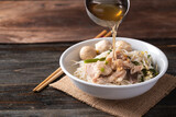 Rice noodles soup with pork and pork ball in a bowl with ladle pouring soup water, Thai noodles soup