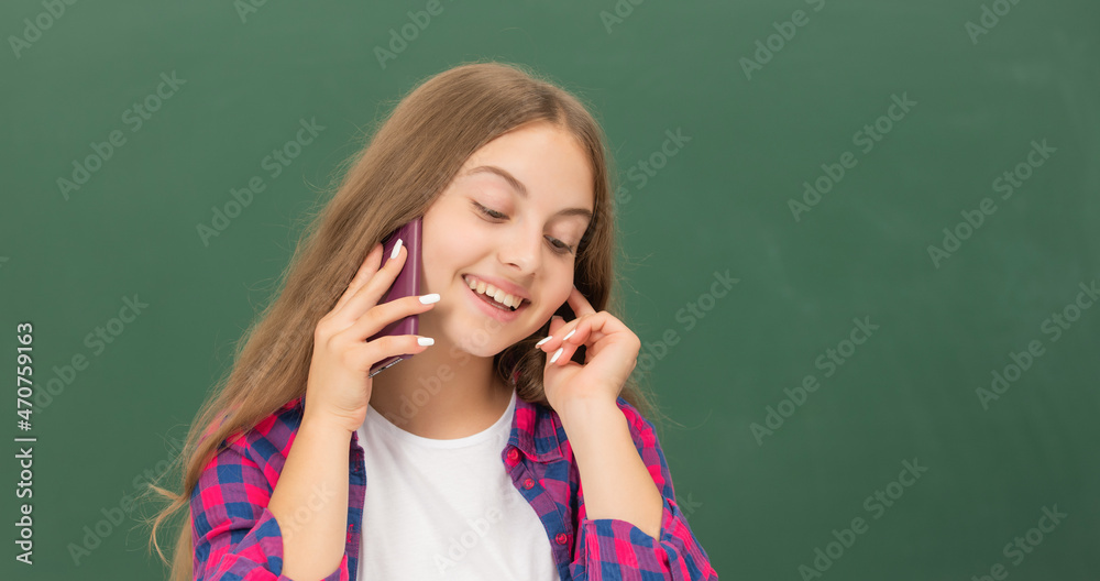 happy kid speaking on smartphone in classroom at blackboard, copy space, conversation happy kid speaking on smartphone in classroom at blackboard, copy space, conversation