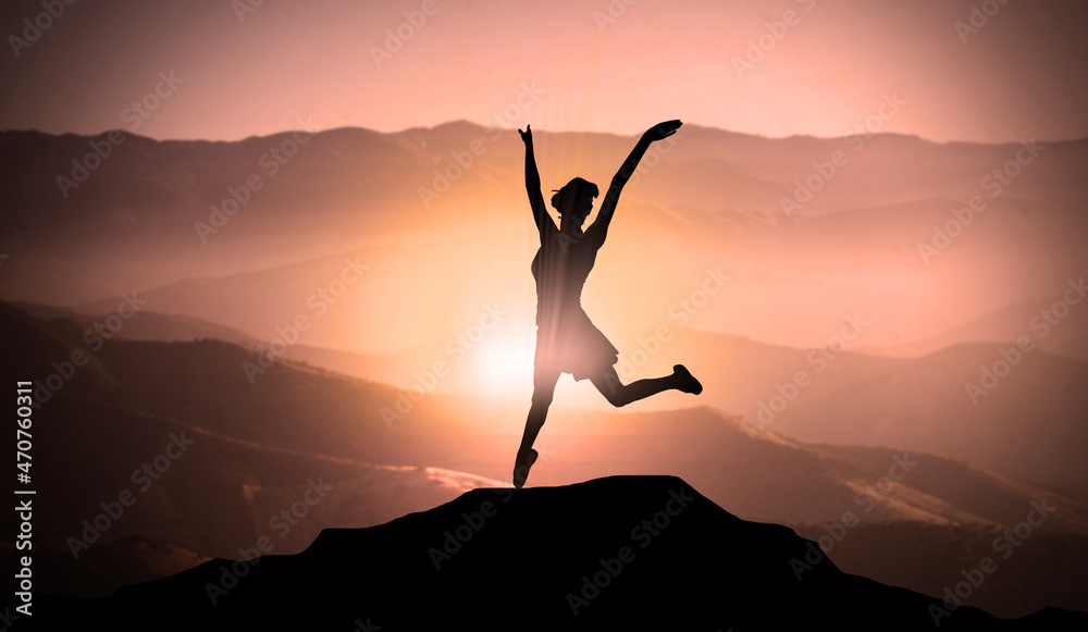 Young Happy Girl Jumps For Joy On The Top of Mountain Peak Above Clouds At Sunset. Free Success Woman and Freedom Concept 
