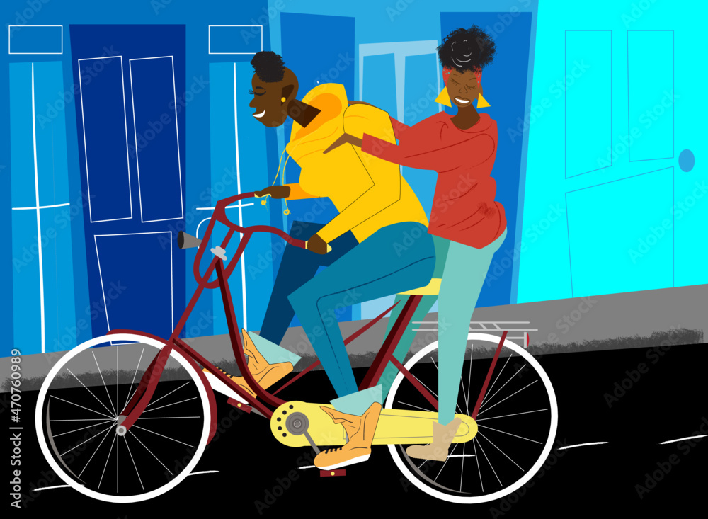 Lesbian woman pedals on bike while partner stands on the back wheel