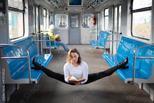 flexible female yogi reading book in the underground carriage sitting in gymnastic split. Concept of inspiration, harmony and health. photo