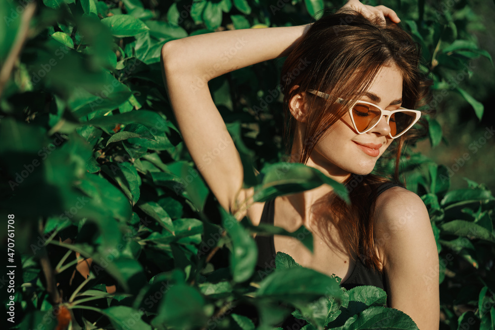 cheerful fashionable woman in sunglasses and green leaves russian summer