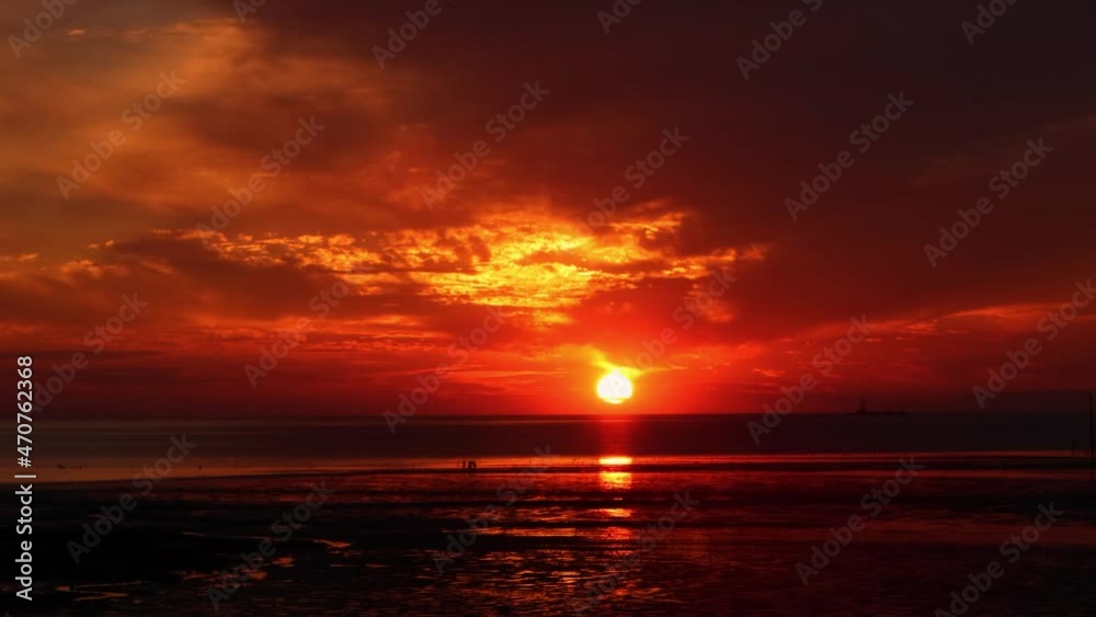 구름사이로 떨어지는 붉은 태양과 바다 갯벌 
