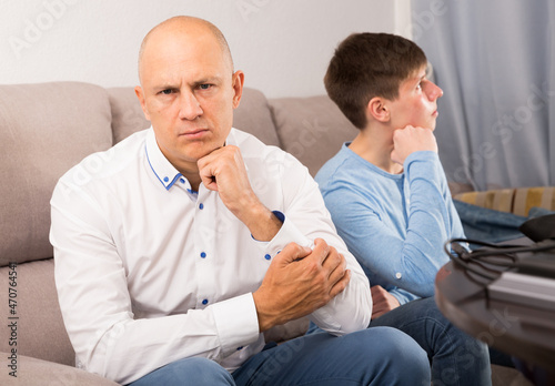 Displeased man dont speaking after discord with teenager son at home photo