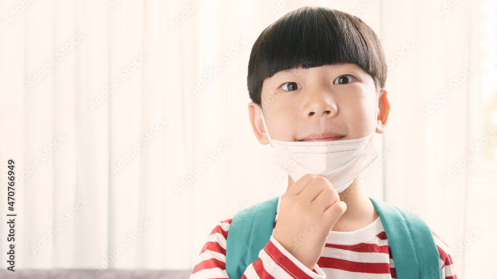 Portrait of a healthy and smart asian student boy smiling under his medical face mask ready to go to school. Back to school, Immune, Copy space, New normal, Living with Covid 19, Vaccinated, Immunity. Portrait of a healthy and smart asian student boy smiling under his medical face mask ready to go to school. Back to school, Immune, Copy space, New normal, Living with Covid 19, Vaccinated, Immunity.