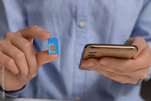 Fotografie Woman with SIM card and smartphone, closeup
