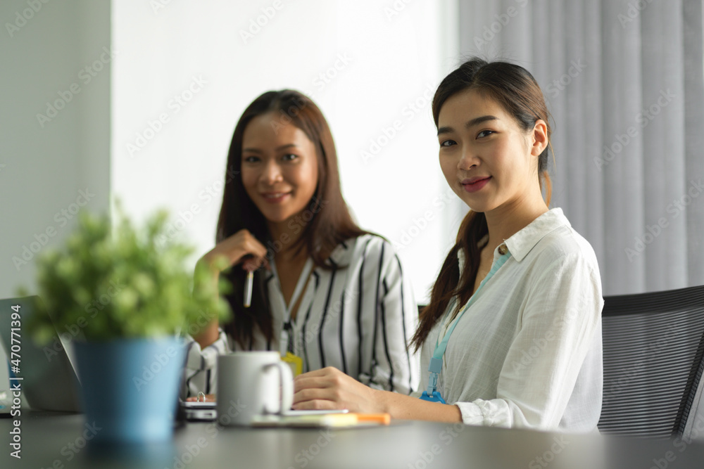 Confident asian businesswomen smile to camera while sits at working desk Confident asian businesswomen smile to camera while sits at working desk