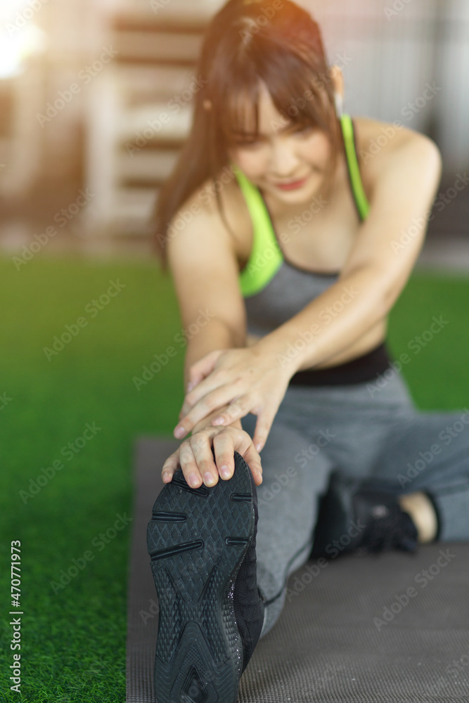 Strong woman stretching legs before workout at the gym.