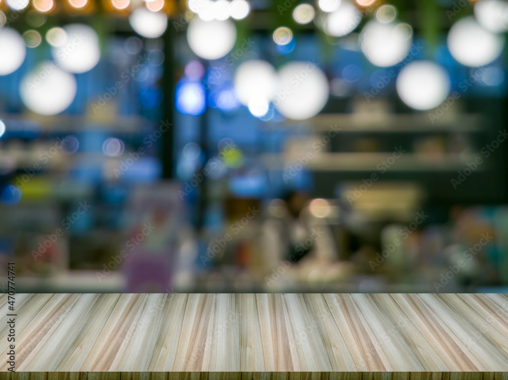 Artificial wood table in front. Blurred background and circular bokeh (big and small), is a shopping mall.