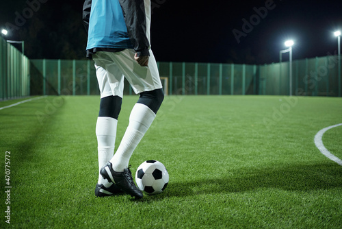 Low section of professional football player going to kick soccer ball while standing on large field during game © pressmaster