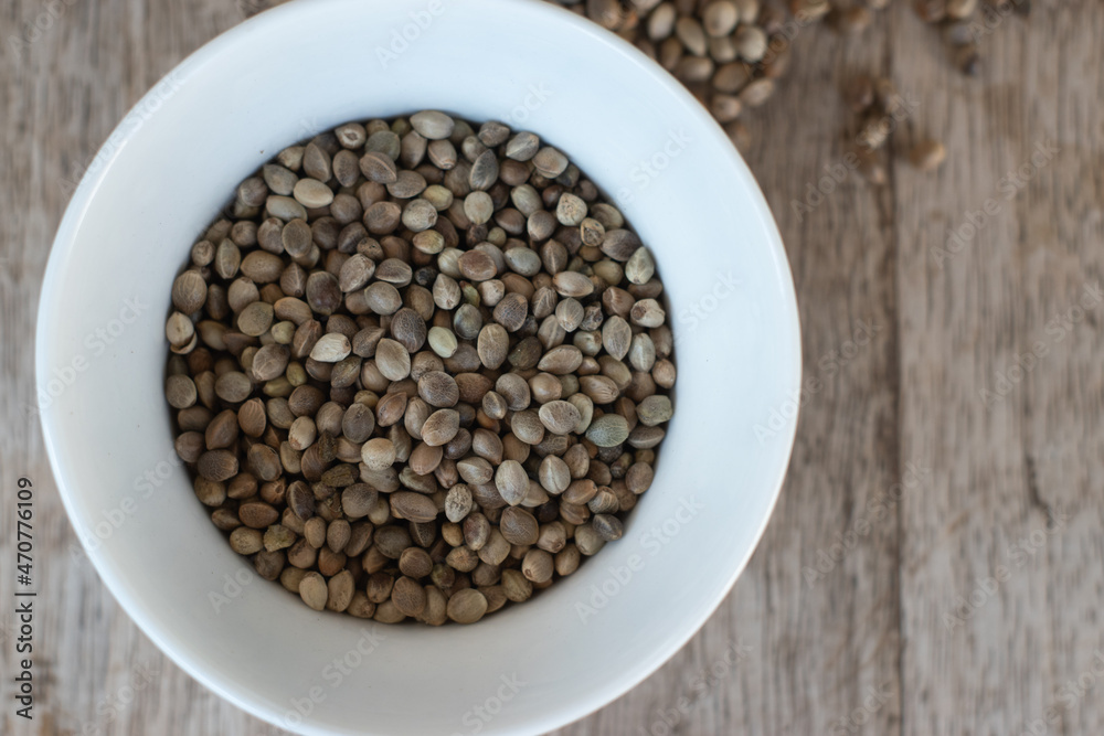 Hemp, Cannabis, Marijuana seeds in a bowl on wooden background. High protein seeds as plant-based food.