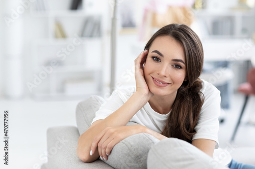 Pretty smiling authentic woman relaxing on couch in living room. Nice weekend.