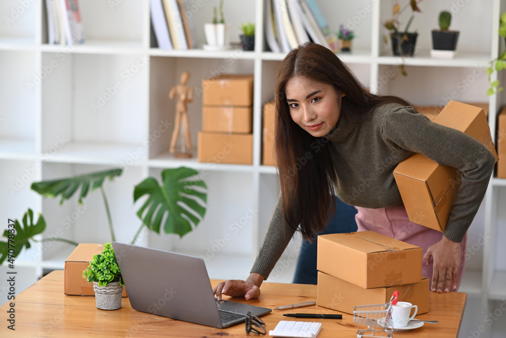 Young start up small business owner using computer laptop and preparing parcel for shipment to customer. Young start up small business owner using computer laptop and preparing parcel for shipment to customer.